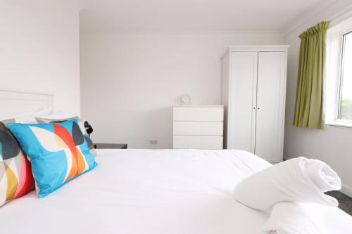 a white bedroom with a large white bed with colorful pillows at Central Bath Getaway with WiFi in Bath
