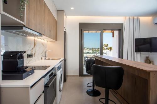 a kitchen with a sink and a counter with two chairs at Nostos Luxury Apartments in Kremasti