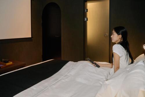 a woman sitting on top of a bed at Cave Ryokan Hotel by Aank Sungshin Women's University in Seoul