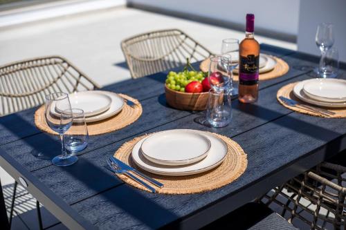 a blue table with plates and a basket of fruit at Nostos Luxury Apartments in Kremasti