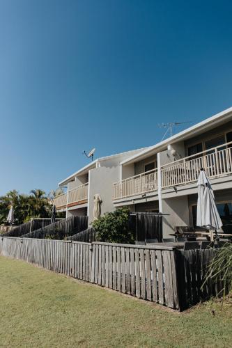 a white building with a fence and an umbrella at Pandanus Palms Holiday Resort in Point Lookout
