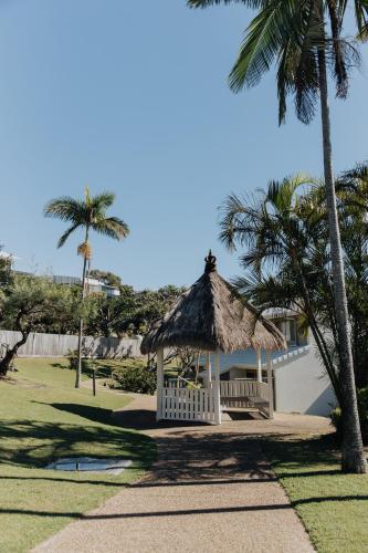 a gazebo with a bench and palm trees at Pandanus Palms Holiday Resort in Point Lookout