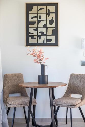 a table with two chairs and a vase with a plant at Nostos Luxury Apartments in Kremasti