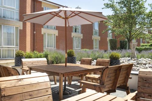 a wooden table and chairs with an umbrella at Hilton Northampton Hotel in Northampton