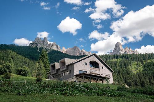 a house on a hill with mountains in the background at Hotel Bewaller in Obereggen