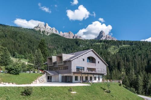 a house on a hill with mountains in the background at Hotel Bewaller in Obereggen