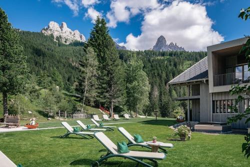 a row of lounge chairs on a lawn in front of a building at Hotel Bewaller in Obereggen