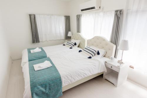 a white bedroom with a large white bed with blue accents at Gracias Arakawa - Great Access to UENO & ASAKUSA area in Tokyo