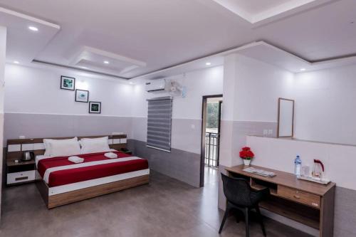 a bedroom with a red bed and a desk and a deskablish at Wayanad West Residency in Kalpetta