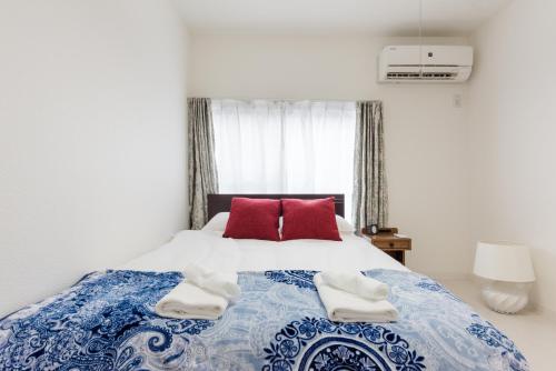 a bedroom with a blue and white bed with red pillows at Gracias Arakawa - Great Access to UENO & ASAKUSA area in Tokyo