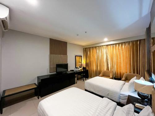 a hotel room with two beds and a desk at Azana Style Hotel Singaraja in Bubunan