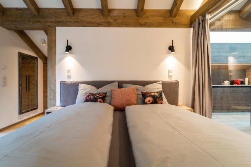two beds in a bedroom with a large window at Detailliebe - Sonne und Stil in Waging am See