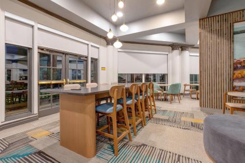a dining room with a bar with chairs and windows at La Quinta by Wyndham Sherman in Sherman