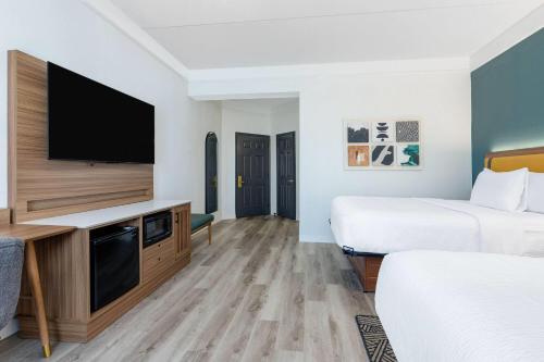 a hotel room with two beds and a flat screen tv at La Quinta by Wyndham Sherman in Sherman