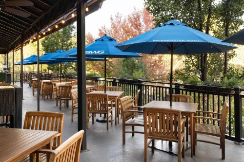 a row of tables and chairs with blue umbrellas at The Golden Hotel, an Ascend Collection Hotel in Golden
