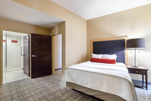 a bedroom with a large bed with a red pillow at Cambria Hotel Pittsburgh - Downtown in Pittsburgh