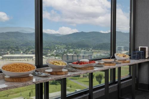 a buffet of bowls of food on a table in front of a window at Embassy Suites By Hilton Pigeon Forge Resort in Pigeon Forge