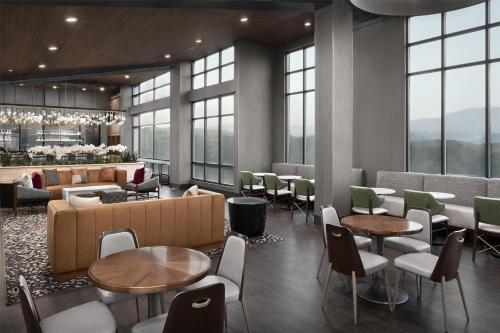 a restaurant with tables and chairs and windows at Embassy Suites By Hilton Pigeon Forge Resort in Pigeon Forge