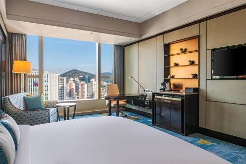 a hotel room with a bed and a desk and a television at Kempinski Hotel Xiamen in Xiamen
