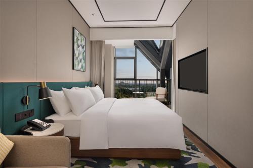 a bedroom with a large white bed and a couch at Hilton Garden Inn Guiyang Gui'An New Area in Guiyang