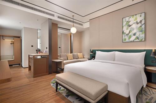 a bedroom with a large bed and a living room at Hilton Garden Inn Guiyang Gui'An New Area in Guiyang