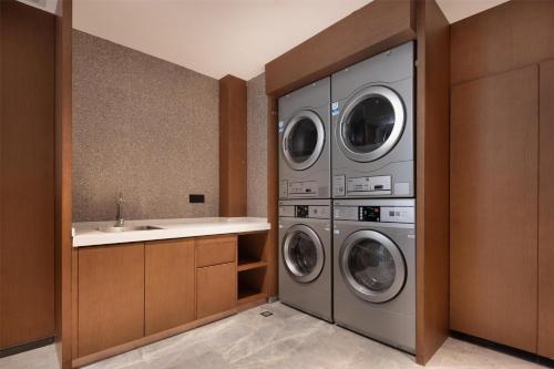 a laundry room with three washing machines and a sink at Hilton Garden Inn Guiyang Gui'An New Area in Guiyang