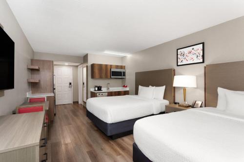 a hotel room with two beds and a kitchen at Hawthorn Extended Stay by Wyndham Ft Lauderdale Cypress Crk in Fort Lauderdale