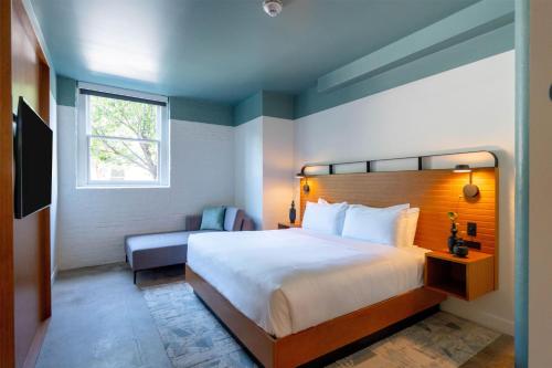 a bedroom with a bed and a chair and a window at The Myriad Hotel Louisville, Tapestry Collection by Hilton in Louisville