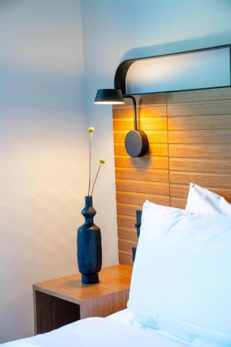 a vase with a flower on a night stand next to a bed at The Myriad Hotel Louisville, Tapestry Collection by Hilton in Louisville