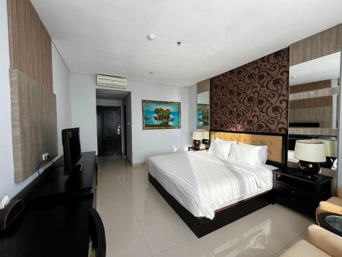 a bedroom with a bed and a television and a couch at Azana Style Hotel Singaraja in Bubunan