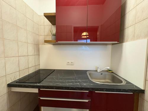 a small kitchen with a sink and red cabinets at Edelweiss Lodge Lachtal I Self Check-in in Lachtal