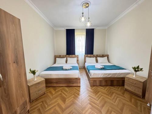 a bedroom with two beds and a chandelier at Hello Batumi Apartment in Batumi