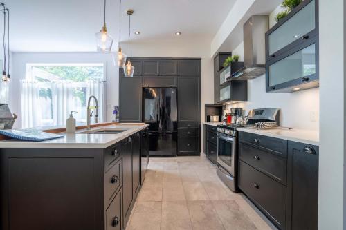 a large kitchen with black cabinets and a sink at Spa River and Comfort - Domaine de la Seigneurie in Sainte Béatrix