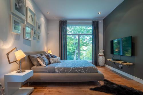 a bedroom with a bed and a large window at Spa River and Comfort - Domaine de la Seigneurie in Sainte Béatrix
