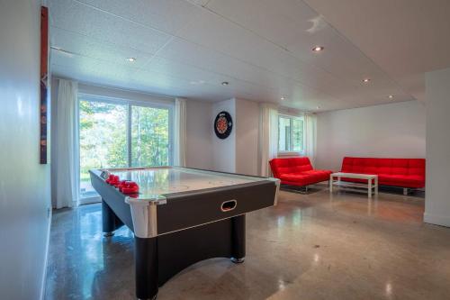 a room with a pool table and red chairs at Spa River and Comfort - Domaine de la Seigneurie in Sainte Béatrix