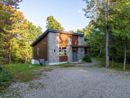 a stone house in the woods with a gravel driveway at Spa River and Comfort - Domaine de la Seigneurie in Sainte Béatrix