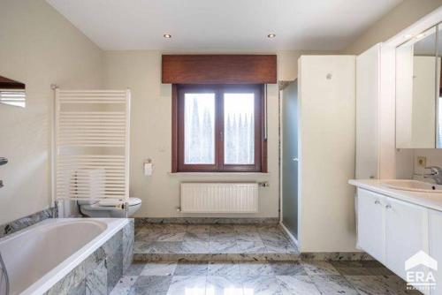 a bathroom with a tub and a toilet and a sink at Villa op de hoek Rooms in Aalst