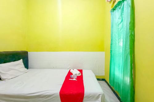 a room with a bed with a red blanket on it at WILUDJENG Guest House near Alun Alun Sragen Mitra RedDoorz in Sragen