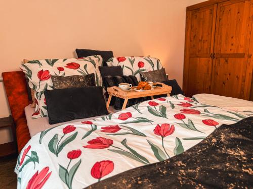 a bed with a blanket with red flowers on it at Chalupa Tylda in Lhota