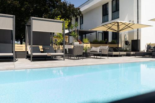 a swimming pool with chairs and an umbrella at Kracher Hotel Doppelzimmer - für maximal 4 Personen inklusive Pool in Illmitz