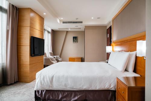 a hotel room with a bed and a flat screen tv at Arsma Hotel in Hualien City