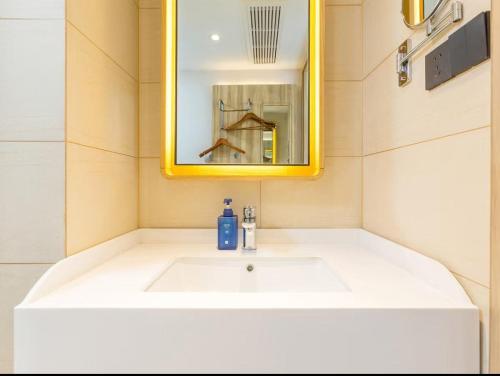 a bathroom with a white sink and a yellow mirror at Hanting Premium Beijing Wudaokou Tsinghua East Gate Hotel in Beijing