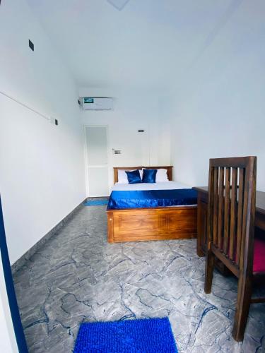a bedroom with a bed and a chair and blue rugs at TK Homes in Badulla