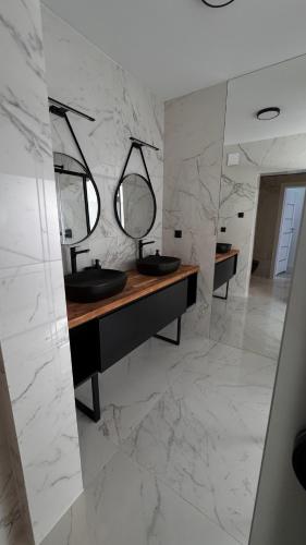 a bathroom with two sinks and two mirrors at Villa Rasmus in Kołobrzeg
