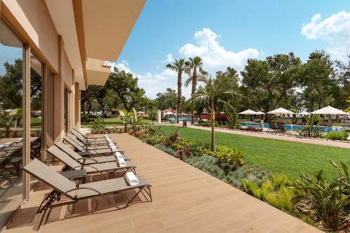 a row of lounge chairs on a porch with a lawn at Akka Antedon Hotel - Premium Ultra All Inclusive in Beldibi