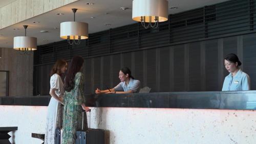 a group of women standing at a counter with luggage at Hotel Monterey Okinawa Spa & Resort in Onna