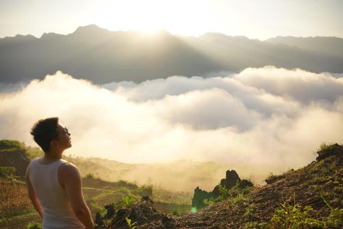 a man standing on top of a mountain looking at the clouds at Homestay Trúc Sơn in Hong Ha