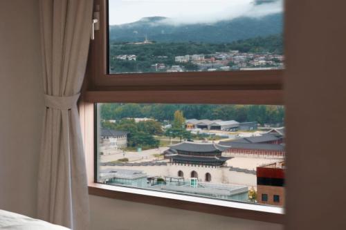 a window in a room with a view of a city at Gyeongbokgung Palace View, 3-min Walk to Gwanghwamun & Jonggak Stations in Seoul