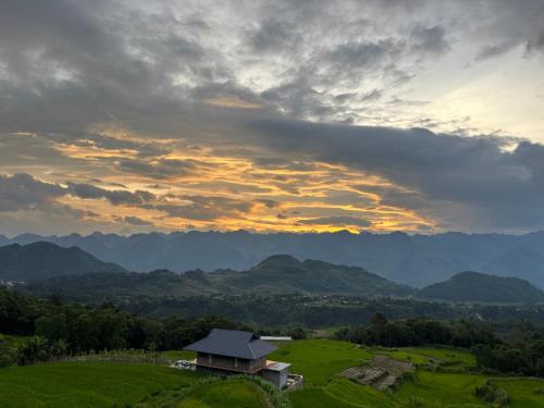a house in a field with mountains in the background at Homestay Trúc Sơn in Hong Ha