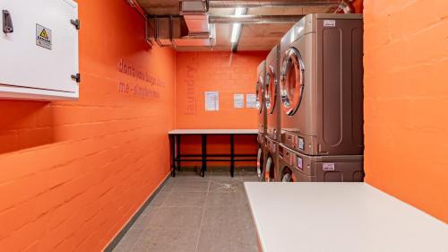 a laundry room with an orange wall and a washing machine at Designer apartment in Sea Point with rooftop pool in Cape Town